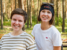 Two SOFTSWISS team members smiling during an outdoor company event in a forest setting.