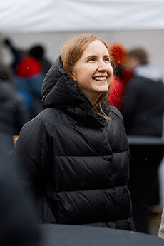 A girl smiling warmly while attending an outdoor event.