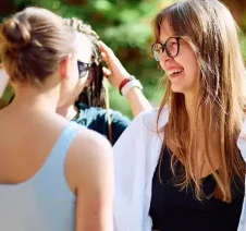 Two women smiling and chatting outdoors during a sunny day.