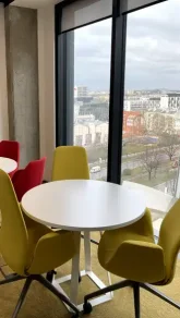 Bright office seating area with colorful chairs and a view of the city through large windows