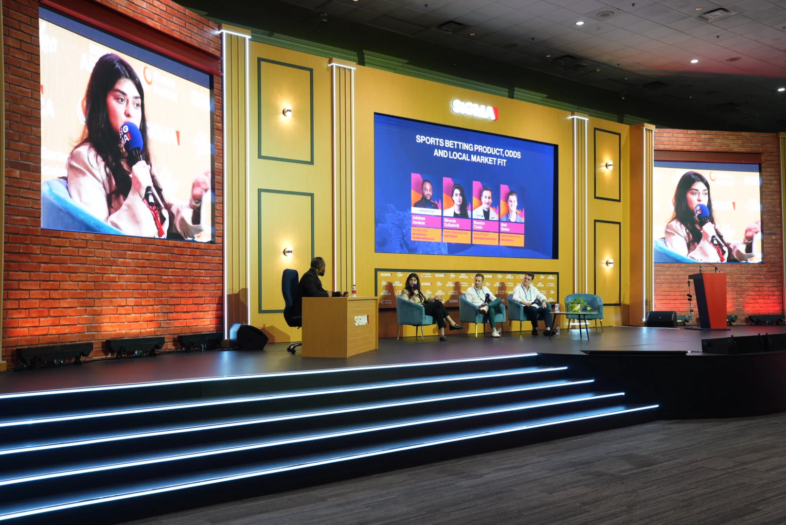 gold background, 5 people sitting in the chairs at the panel discussion