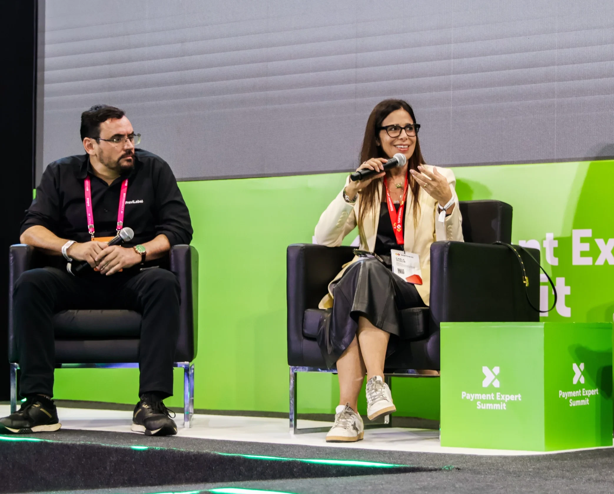 Man and woman on the chairs, public speaking, green background